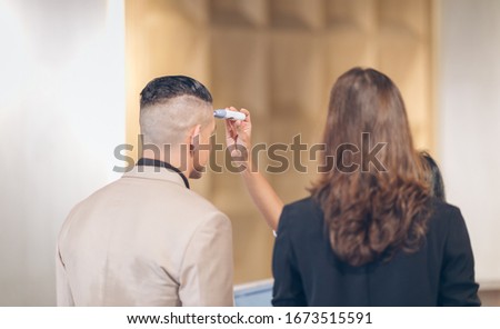 checking temperature tourist, female receptionist at counter in hotel