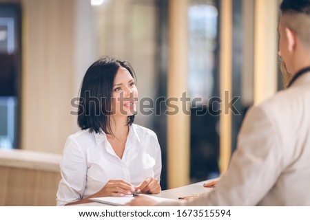female receptionist at counter in hotel with Young couple receiving tourist information