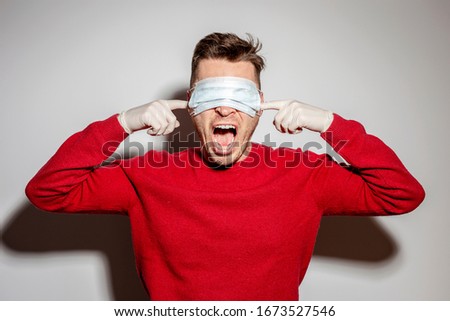 Coronavirus pandemic. A man in a medical mask on his eyes, so as not to see the ears, put his hands over his ears in medical gloves so as not to hear