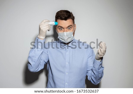 Coronavirus pandemic. A man in a medical mask and medical gloves measures body temperature with an electronic thermometer.