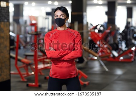 Coronavirus covid-19 prevention, fitness girl with a medical mask posing in gym. Fighting viruses. Royalty-Free Stock Photo #1673535187