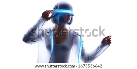 Beautiful woman with purple hair in futuristic costume over white background. Girl in glasses of virtual reality. Augmented reality, game, future technology, AI concept. VR. Blue neon light. Royalty-Free Stock Photo #1673536642