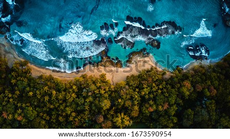 Aerial drone photo of a blue tropical lagoon surrounded by white sand of an exotic beach and palm trees.