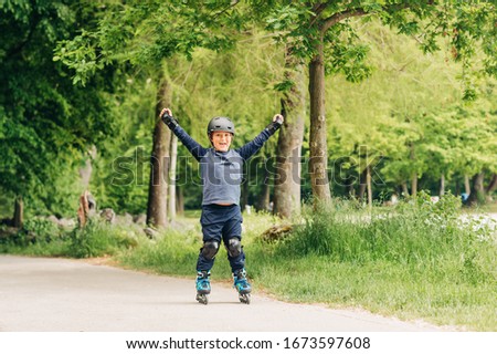 Active little boy skating in summer park, healthy lifestyle for children, holding arms up wide open