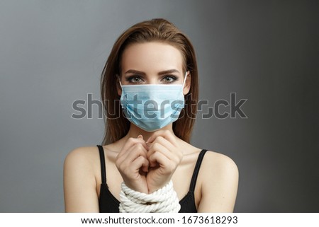 Woman with tied hands in a medical mask on a gray background studio photo Violent action concept Human trafficking Kidnapping Nurse wearing respirator mask, Coronavirus and covid-19 concept