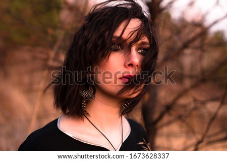 Boho young woman at sunset. Portrait with sunlight in forest. Dark make up