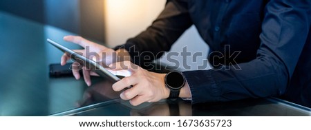 Businessman hand using digital tablet in office meeting room. Male entrepreneur reading news on social media app. Online marketing and Big data technology for E-commerce business. 