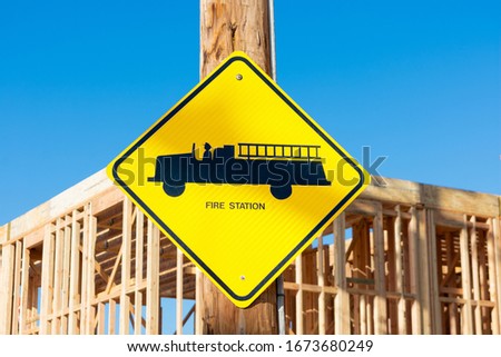 Fire station road sign with fire engine. Blurred background wood framing construction of new residential building. Beautiful blue sky.