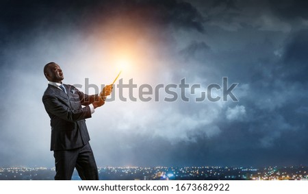 Conceptual image of ambitious and creative businessman in black suit holding paintbrush in hand