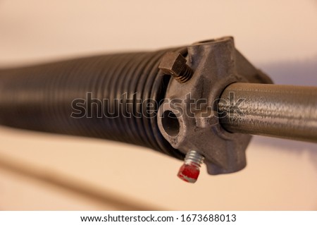 Close up side view of garage door coiled spring Royalty-Free Stock Photo #1673688013