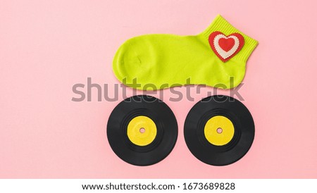 Women's sports sock on two vinyl discs on a pink background. The concept of music and sports. Flat lay.