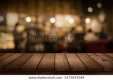 Wood table top on blur bokeh coffee shop or cafe restaurant background. Can be used for display or montage your products.