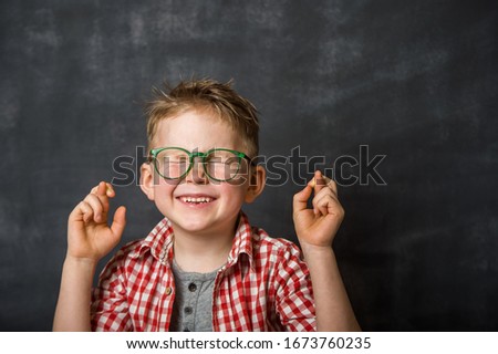 School boy with crossed fingers makes a wish. Funny  child portrait with emotional face and closed eyes