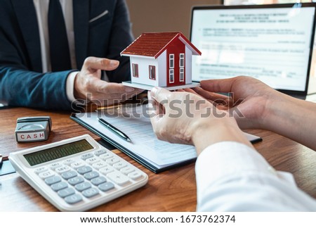 Sale purchase contract to buy a house, Real estate agent are presenting home loan and giving keys to customer after signing contract to buy house with approved property application form.