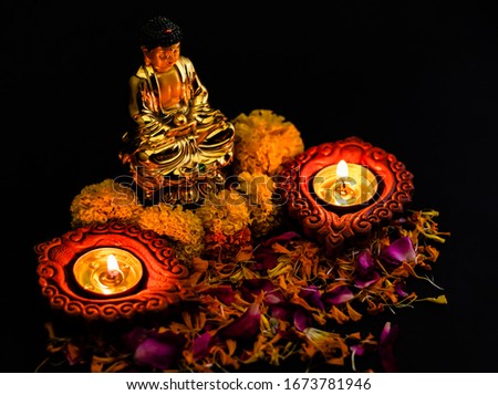 two clay lamp glowing on flower petals with buddha statue over 
