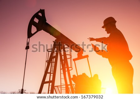 Oil Drill, field pump jack silhouette with setting sun and worker.Refinery, natural gas. Lens Flare. See more images and video from this series 
