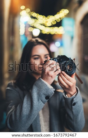 Photographer with retro camera take photo on background bokeh light in night city, Blogger photoshoot concept. Tourist  travels