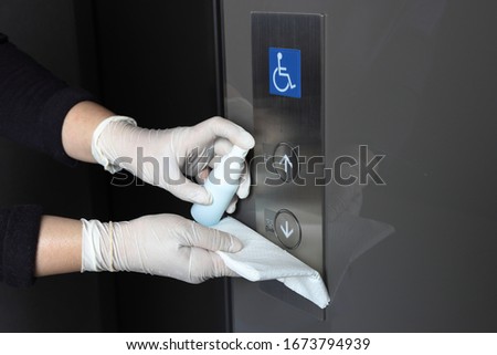 Cleaning staff Cleaned elevator switch button in hospital with alcohol spray and wipe out with clean paper. Corona Virus or bacteria infected protection from touch public object.  Royalty-Free Stock Photo #1673794939