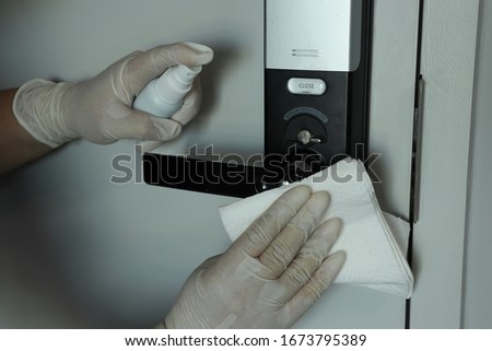 Cleaning staff Cleaned door knob and electrical door locked with alcohol spray and wipe out with clean paper. Corona Virus or bacteria infected protection from touch public object.  Royalty-Free Stock Photo #1673795389