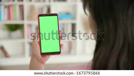 woman use smart phone with green screen at home