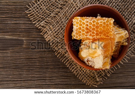 Honeycomb pieces in ceramic bowl close up on wooden table background with copy space Royalty-Free Stock Photo #1673808367