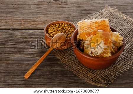 Honey combs in ceramic bowl , bee pollen and dipper on rustic wooden table