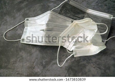 Dramatic image. Used surgical face mask on gray floor. Dirty and many disease. Should be destroy (cut) and separating before throw it in bin. Cannot reuse. Health care concept. Copy space. Royalty-Free Stock Photo #1673810839