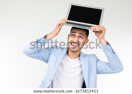 smiling young brunette man holding a laptop screen to the camera with a blank mockup on a white background