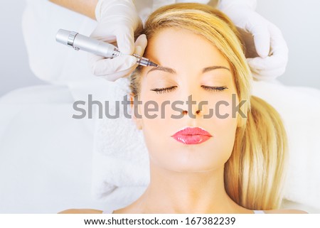 Cosmetologist applying permanent make up on eyebrows 