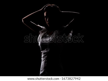 Silhouette of a beautiful slender girl in a white dress on a black background