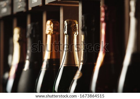 Bottles of champagne on the shelf, close-up image of alcoholic beverages in the wine cellar. Close-up image. Royalty-Free Stock Photo #1673864515