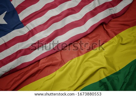 waving colorful flag of bolivia and national flag of liberia. macro