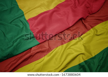 waving colorful flag of bolivia and national flag of benin. macro
