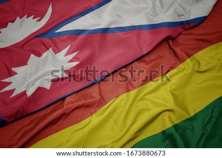 waving colorful flag of bolivia and national flag of nepal. macro