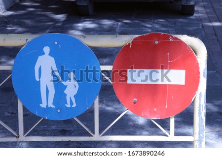 Blue pedestrian traffic sign with man and child as a symbol next to red sign