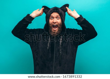 Cheerful bearded man in black cat kigurumi pajama. Crazy emotions. Pajamas party