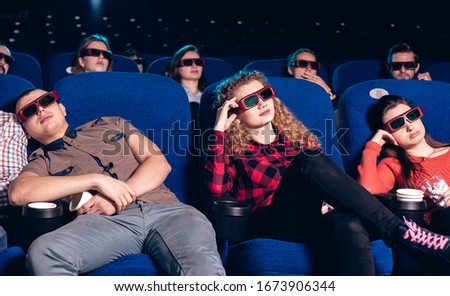 People in a movie theater are sitting and watching a boring movie in 3D glasses. Stock photo of a group of people in the cinema.
