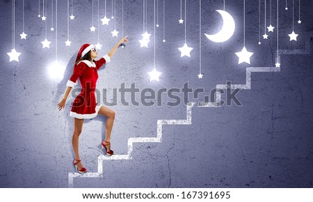 Attractive young woman in Santa suit walking on ladder