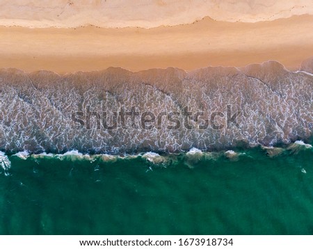 Beach aerial view of ocean water and sand shore.