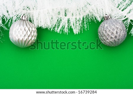 White garland on green background with silver glass balls, Christmas background