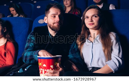 Love couple in the cinema are sitting and watching a movie. Stock photo of a group of people in the cinema.