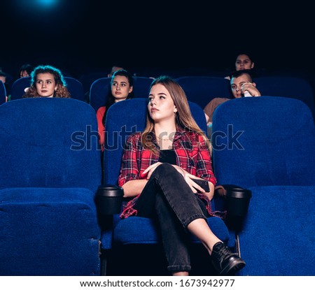 Lonely girl watching a movie at the cinema. Stock photo of a group of people in the cinema.