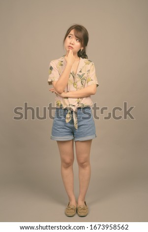 Young beautiful Asian tourist woman ready for vacation against gray background