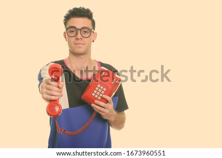 Studio shot of young man giving old telephone