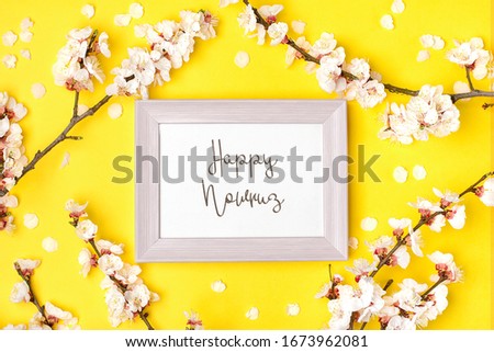 Pink photo frame and sprigs of the apricot tree with flowers on yellow background. Text Happy Nawruz. The concept of spring came Top view. Flat lay Holiday card