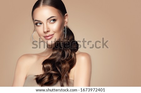 Beautiful girl . Fashionable and stylish woman in trendy jewelry big earrings .Curly ponytail hairstyle.  Fashion look  , beauty and style. Natural makeup and cosmetics Royalty-Free Stock Photo #1673972401