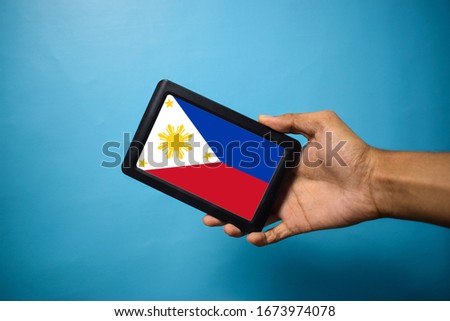 Man holding Smartphone with Flag of Philippines. Philippines Flag on Mobile Screen isolated On Blue Background