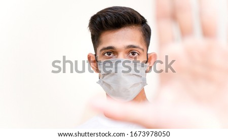 Young Asian boy wearing protective mask against the corona virus covid 19 and stopping people to interact with each other brown man with surgical mask to prevent from virus white background blur hand