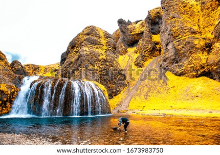 Photographer taking pictures of amazing waterfalls in autumn season. Adventure and travel concept.