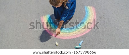 child draws with chalk on the pavement. Selective focus. Royalty-Free Stock Photo #1673998666